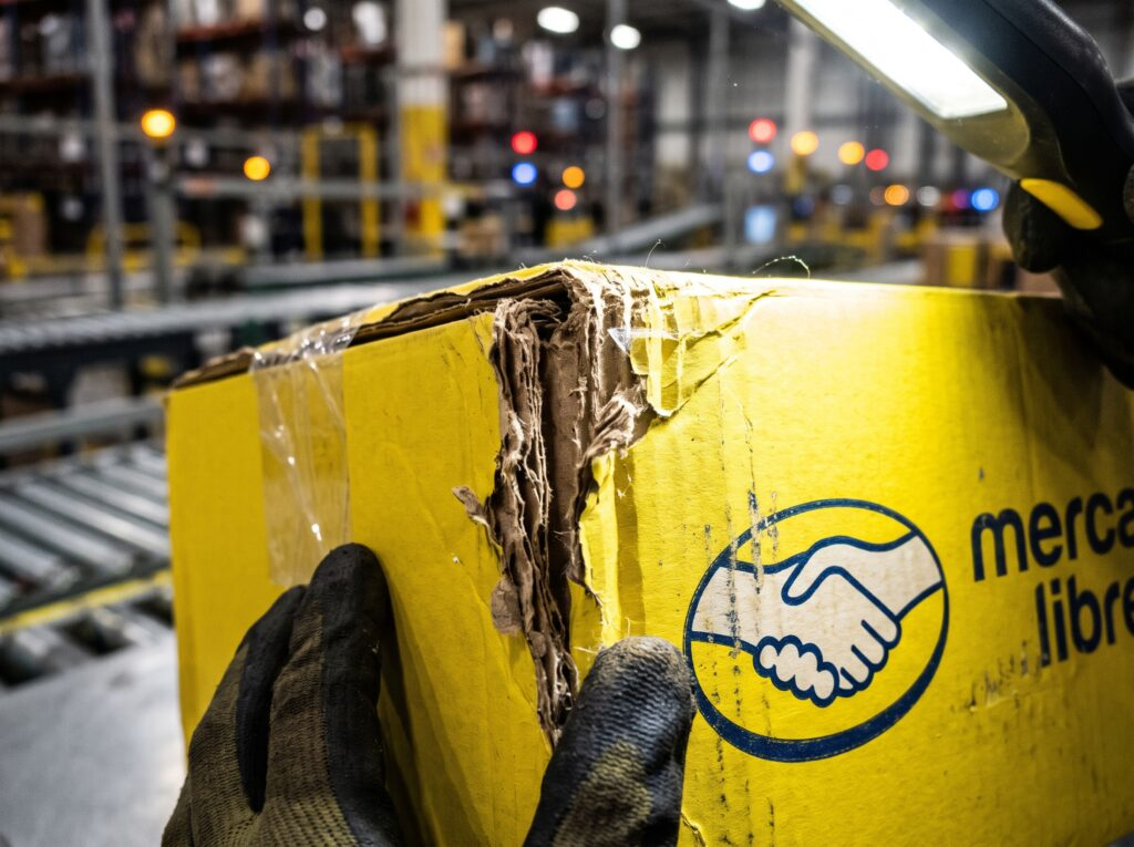 Inspección de paquetería en un centro logístico con empaque oficial de Mercado Libre, plataforma actualmente bajo supervisión de la PROFECO tras el incremento de quejas por entregas irregulares y vendedores apócrifos.